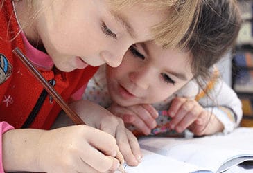 two kids at school reading and writing