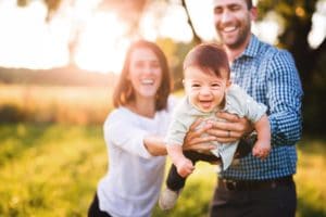 little boy laughing with parents holding him