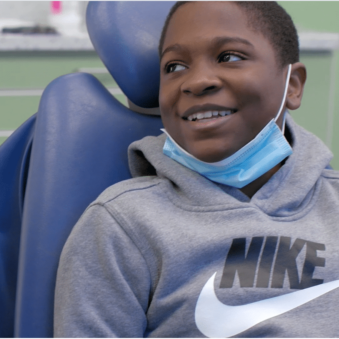 child in patient chair with mask